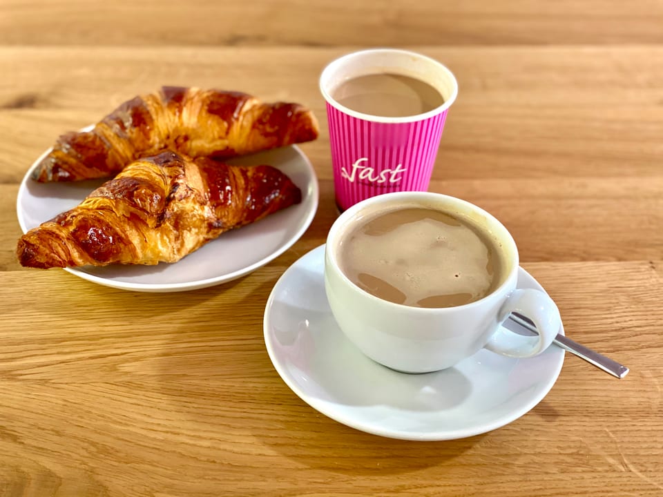 Dos cafés y croissants servidos sobre una mesa de madera
